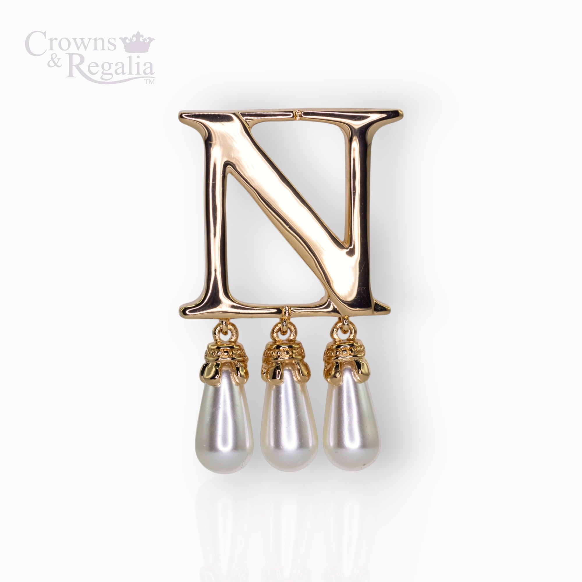 Gold brooch with letter 'N' and pearl-like droplets on a white background, branded 'Crowns & Regalia'.