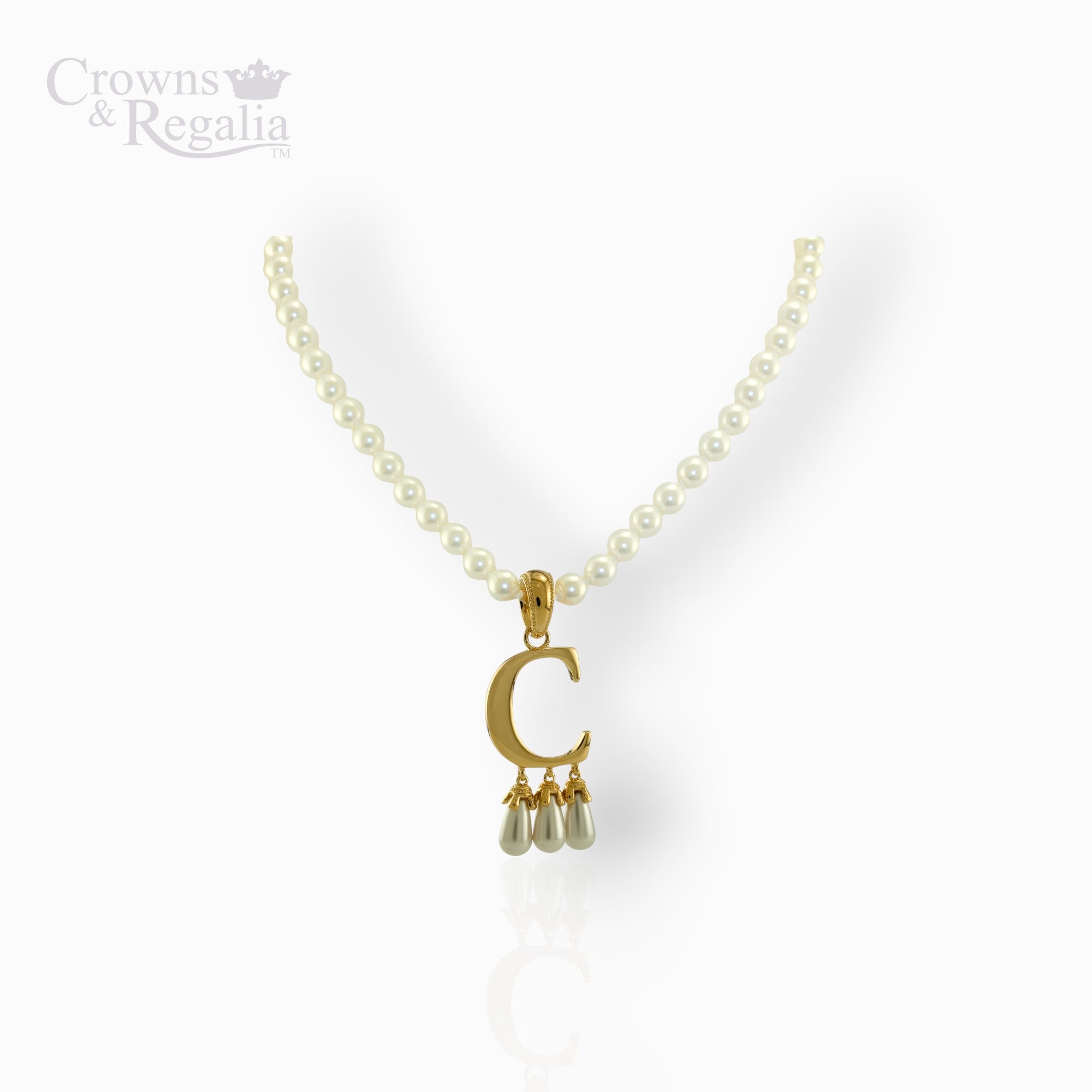 Gold necklace with a 'C' pendant and pearl drops on a white background, branded 'Crowns & Regalia'.