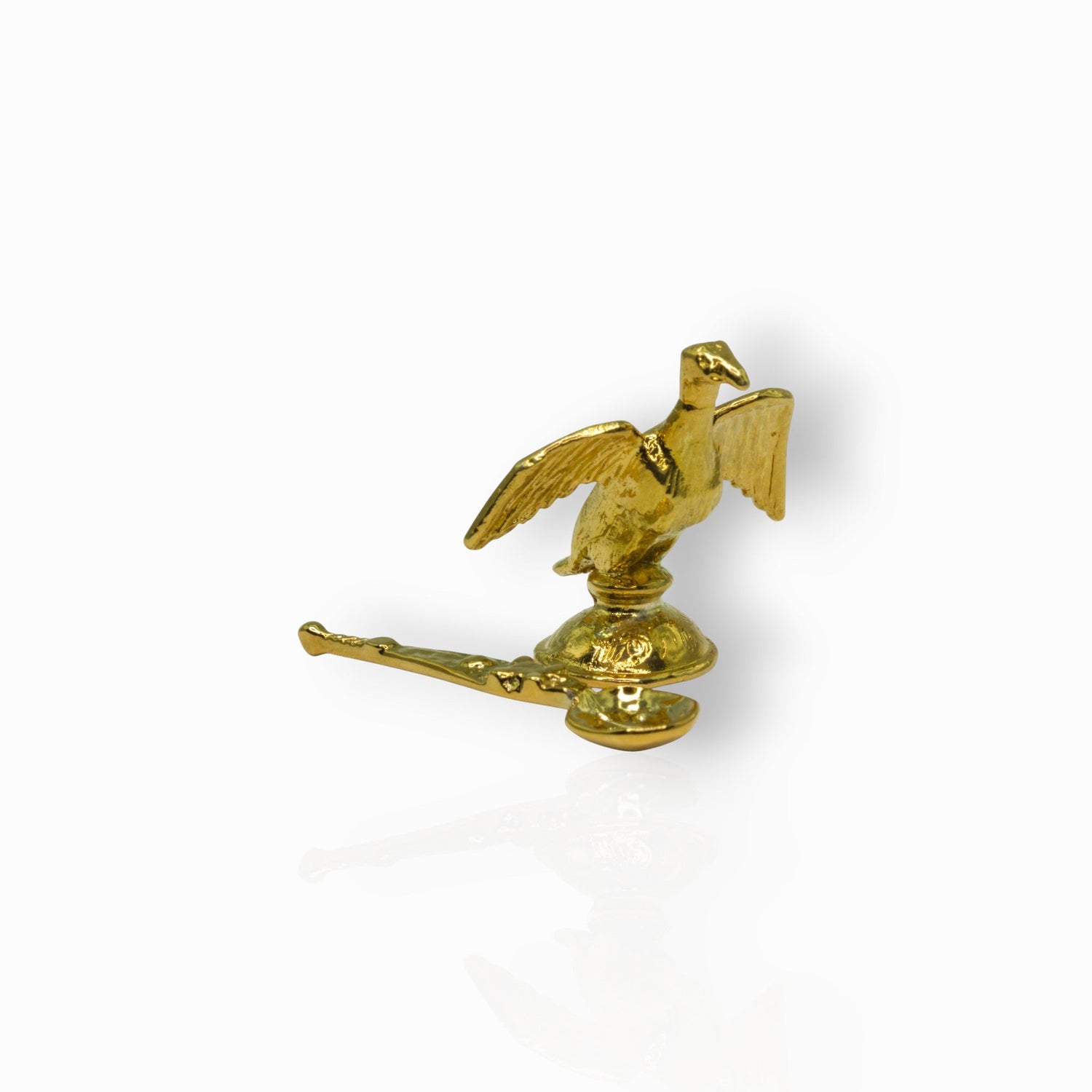 Gold decorative item with a bird design on a white background