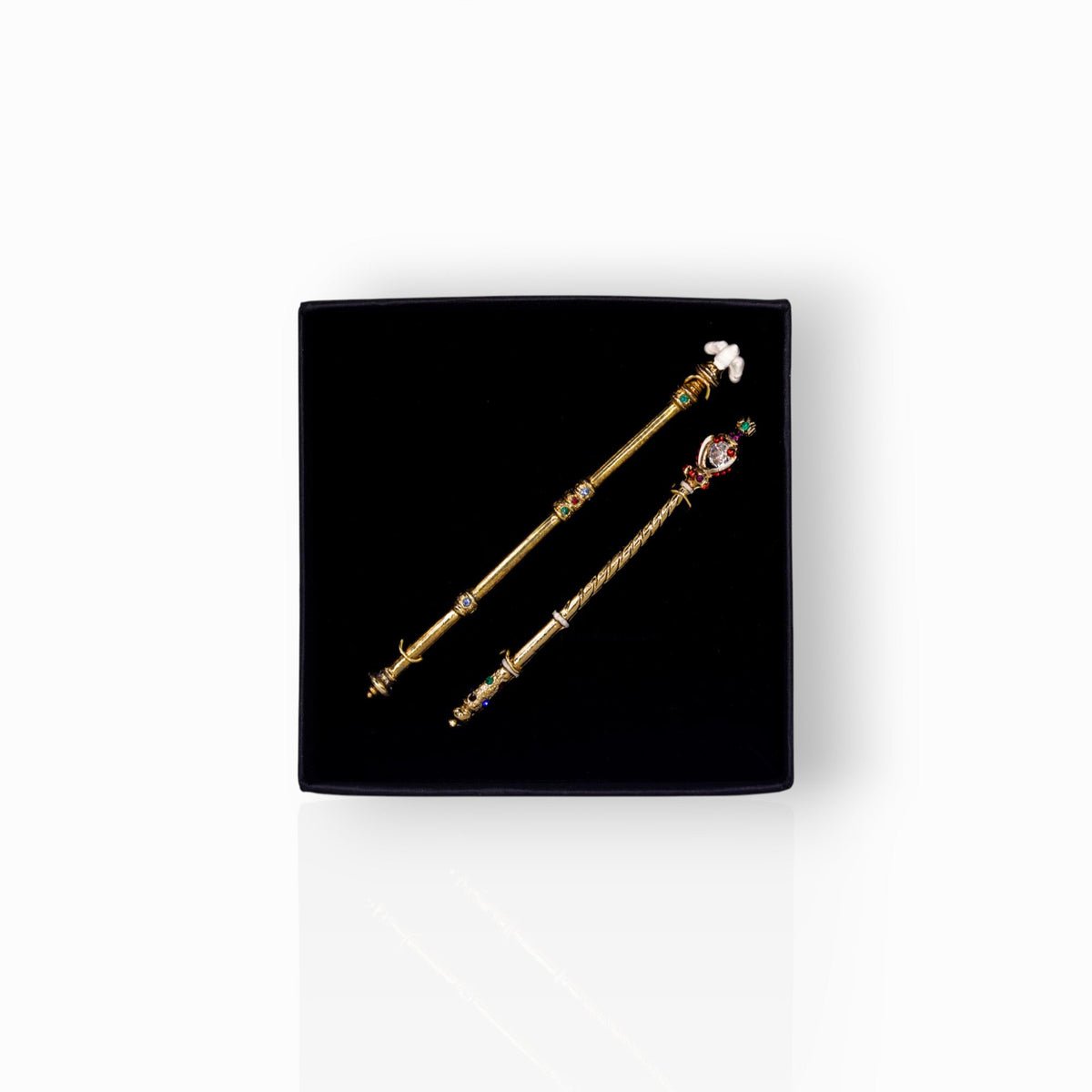 Two decorative sceptres on a black display box.