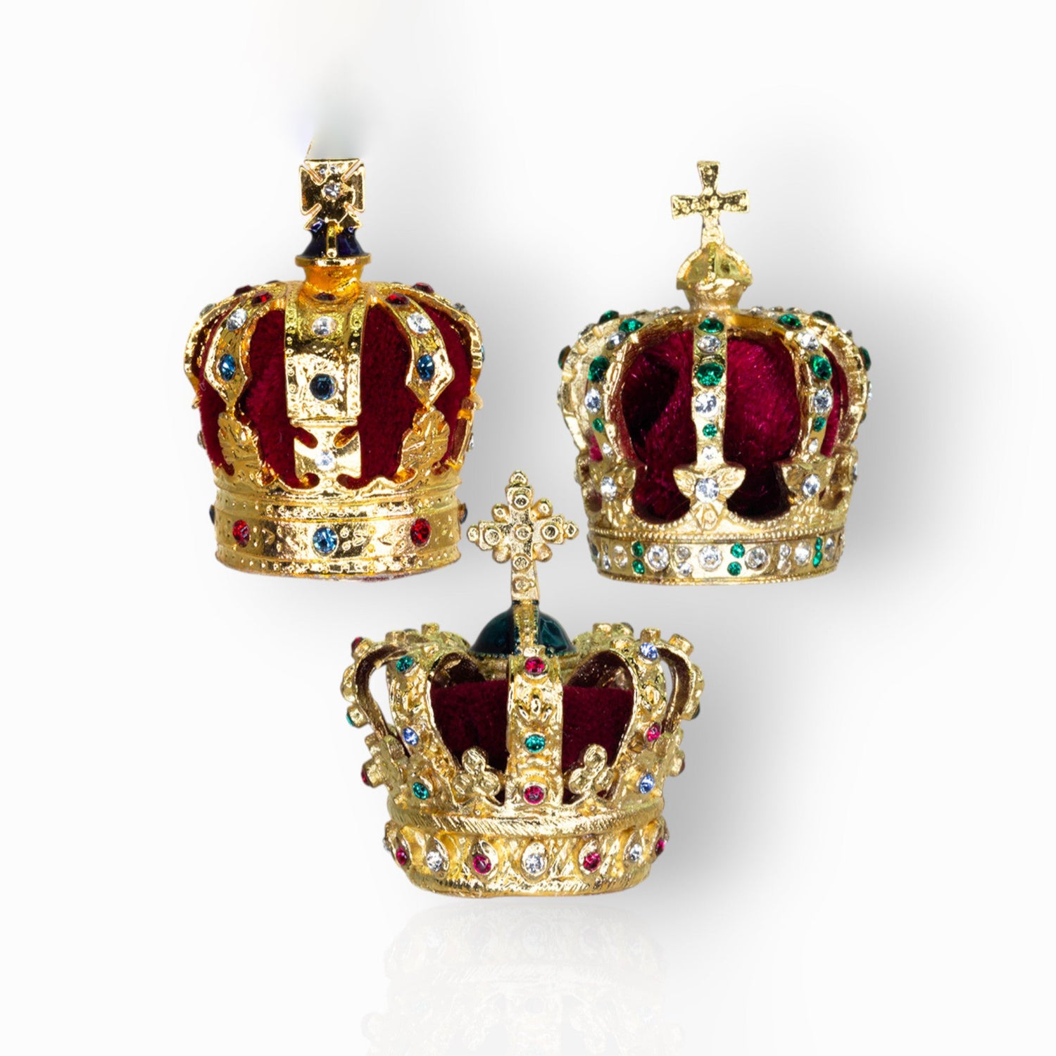 Three ornate crowns with red velvet interiors and gold exteriors on a white background.