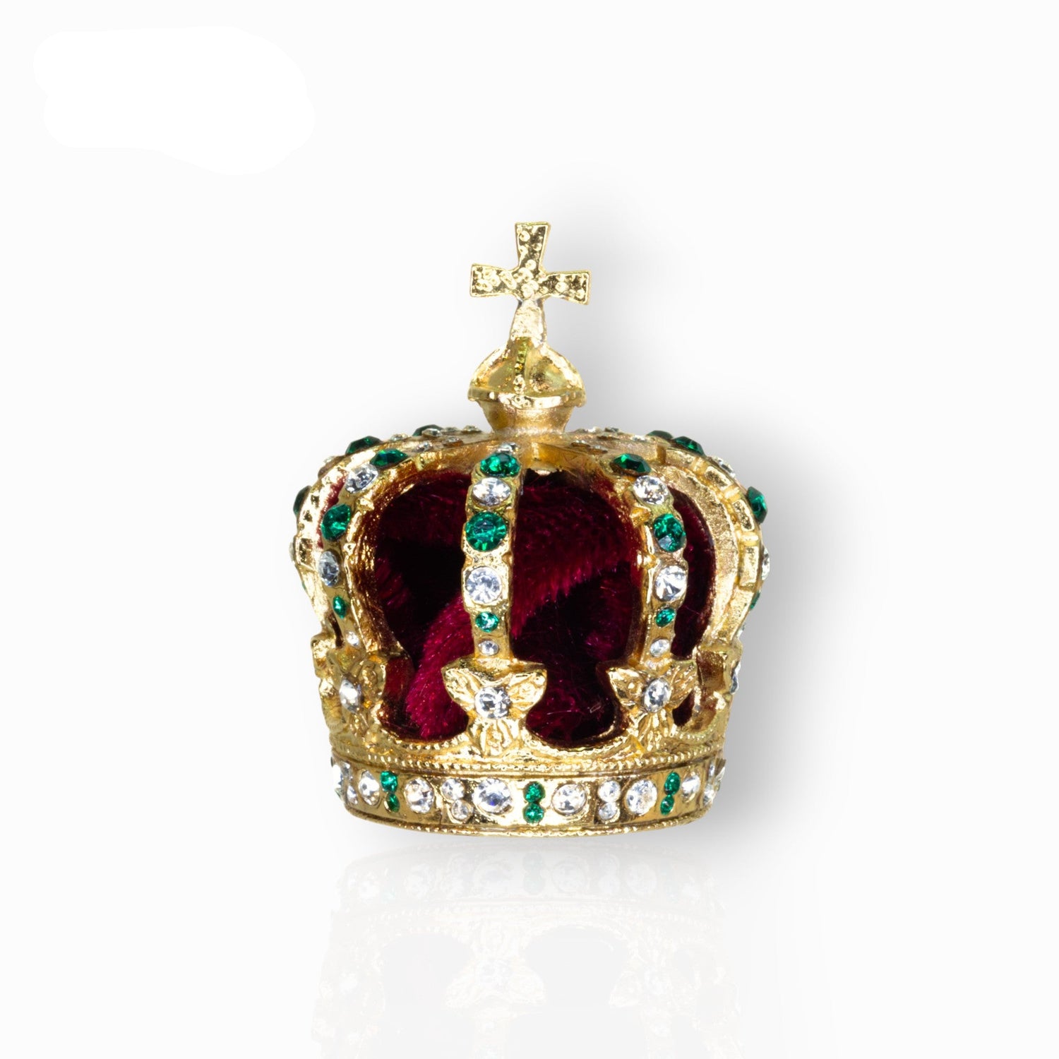 Gold crown with red velvet interior and green gemstones on a white background.