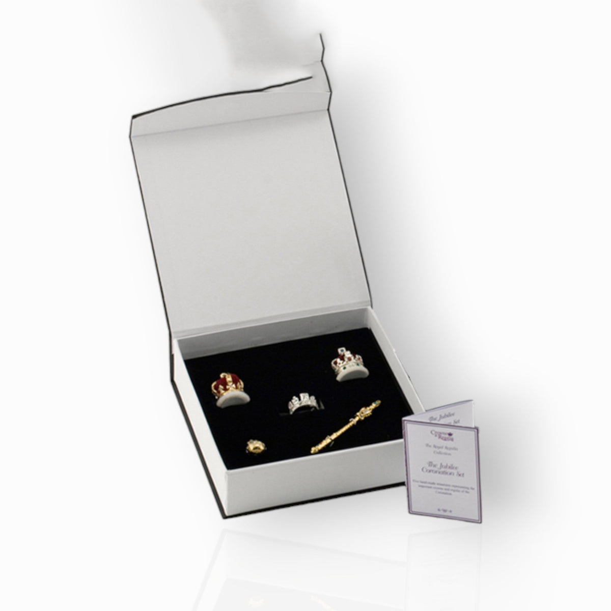 Jewelry set with tiaras and a scepter in a box on a white background.