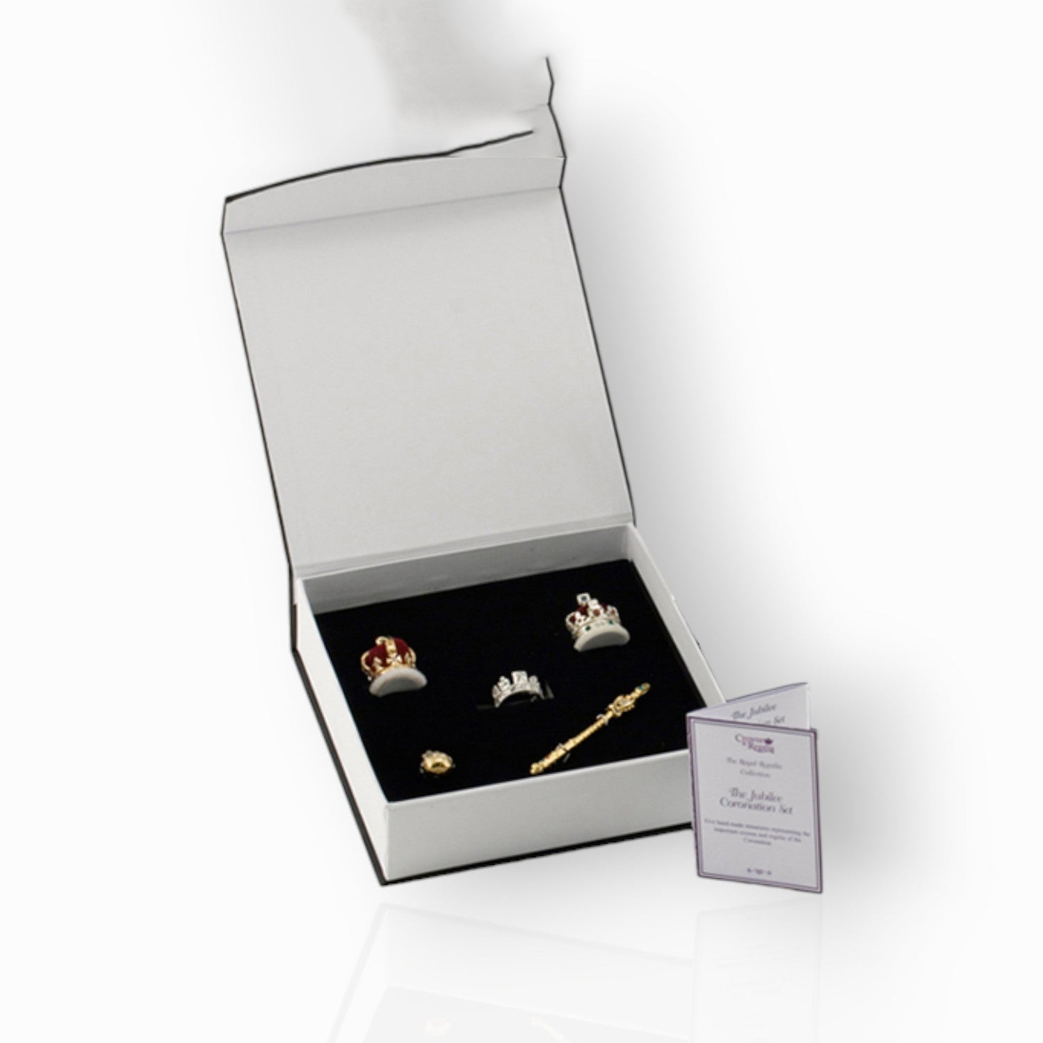 Jewelry set with tiaras and a scepter in a box on a white background.