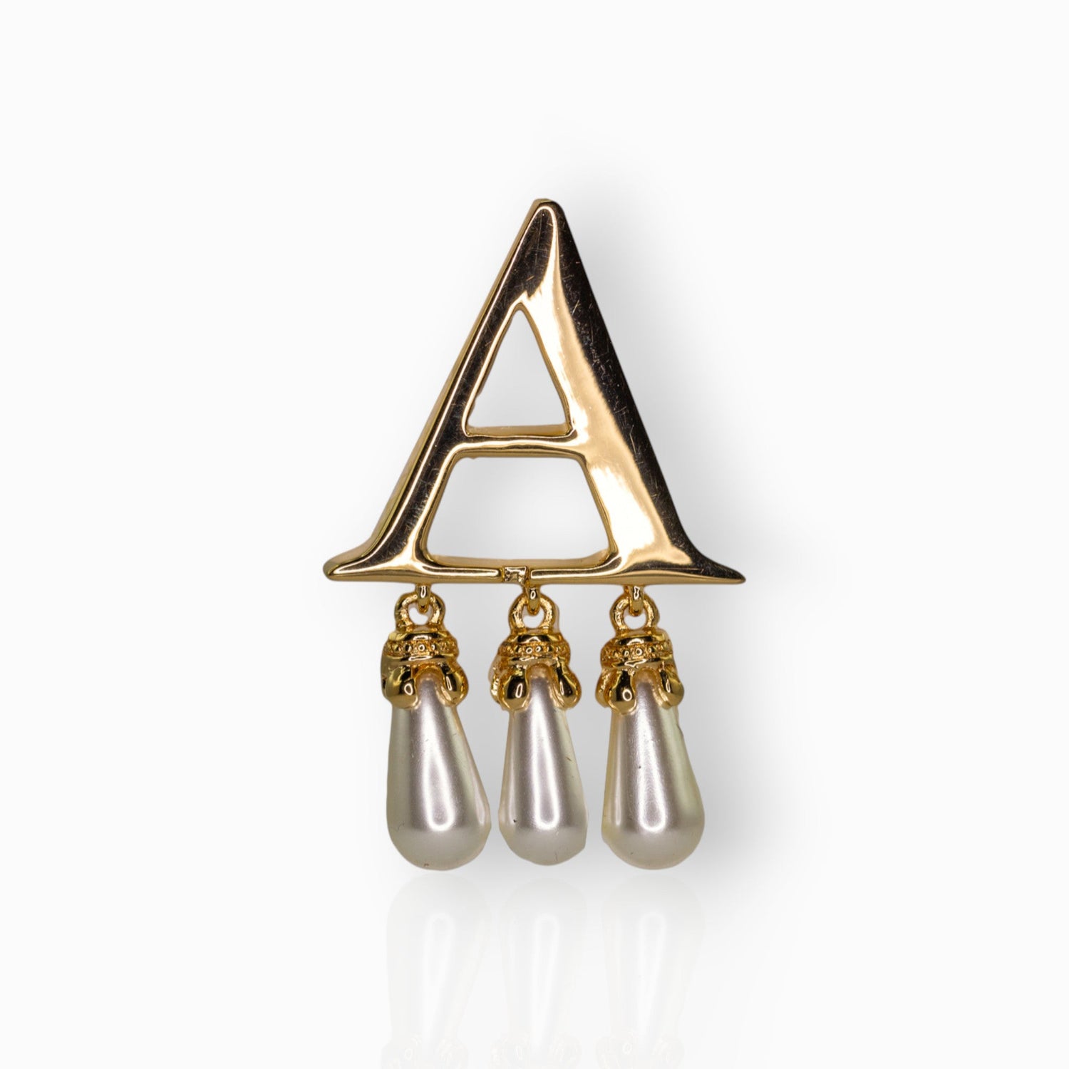 Gold brooch with 'A' and pearl drops on a white background.