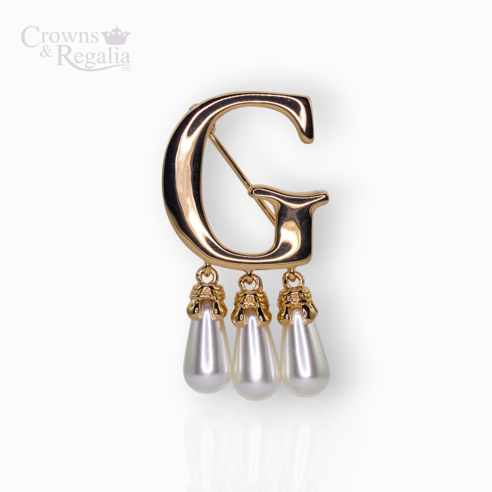 Gold brooch with letter 'G' and pearl-like droplets on a white background, branded 'Crowns & Regalia'.