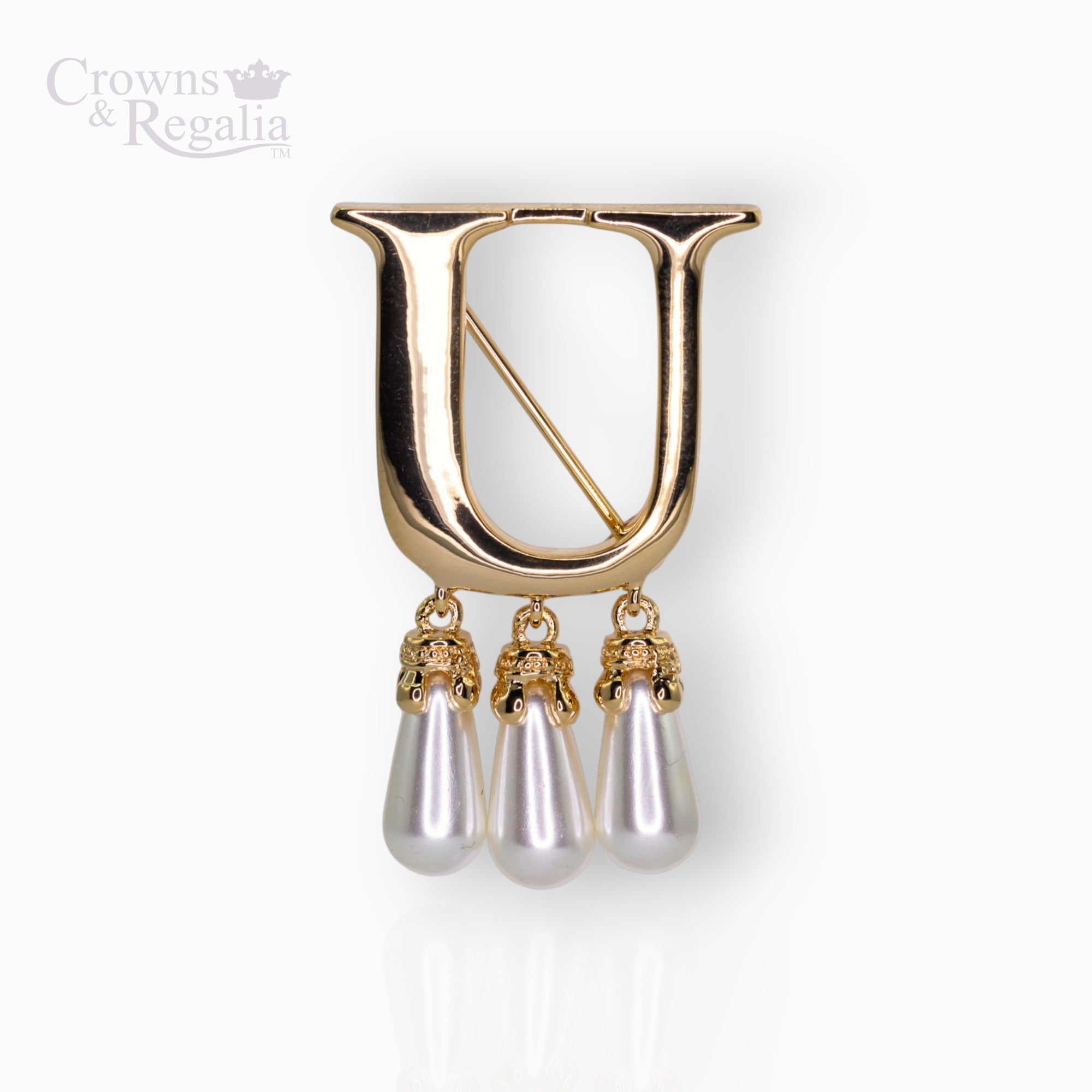 Gold brooch with 'U' and pearl-like droplets on a white background, branded 'Crowns & Regalia'.