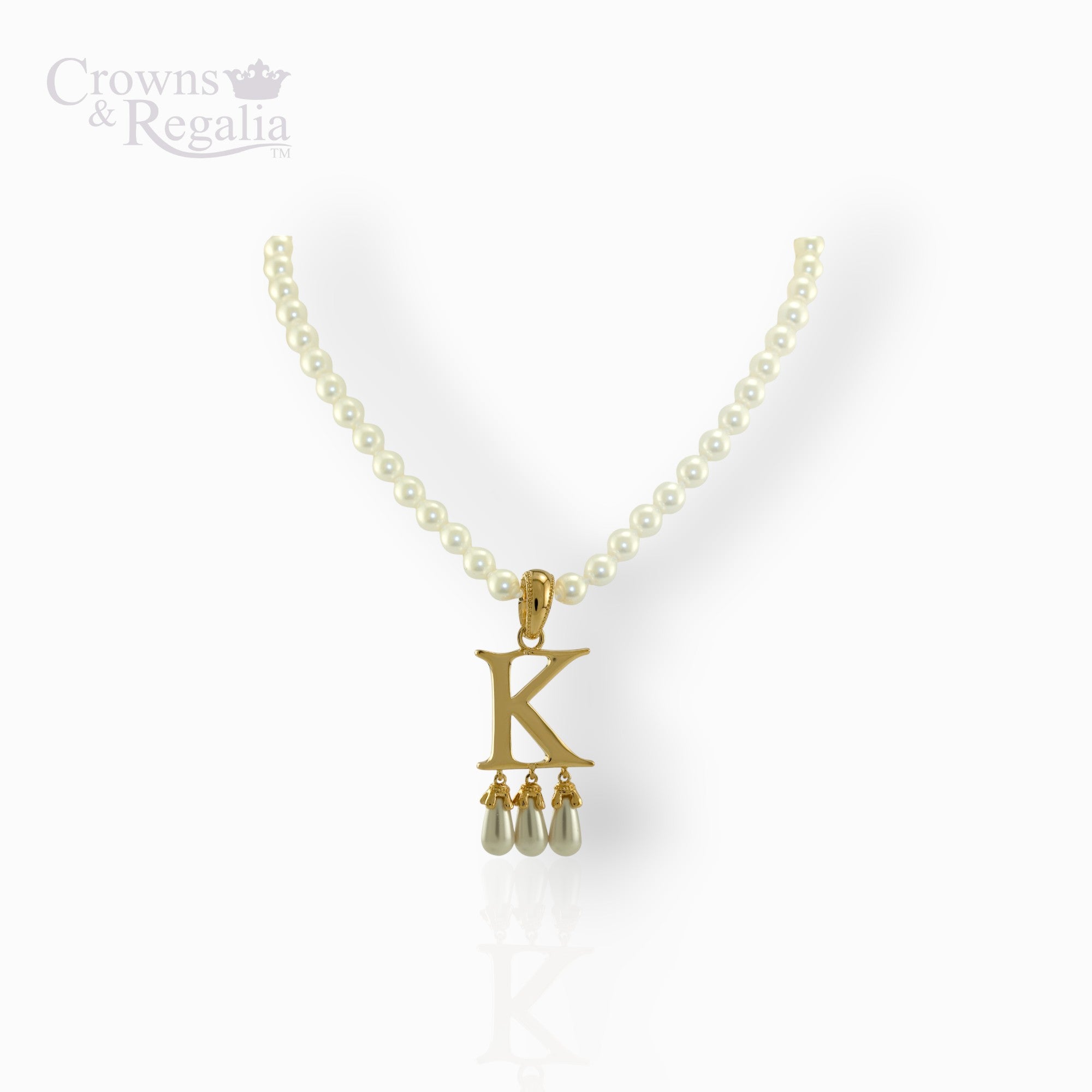 Gold necklace with 'K' pendant and pearl drops on a white background, branded 'Crowns & Regalia'.
