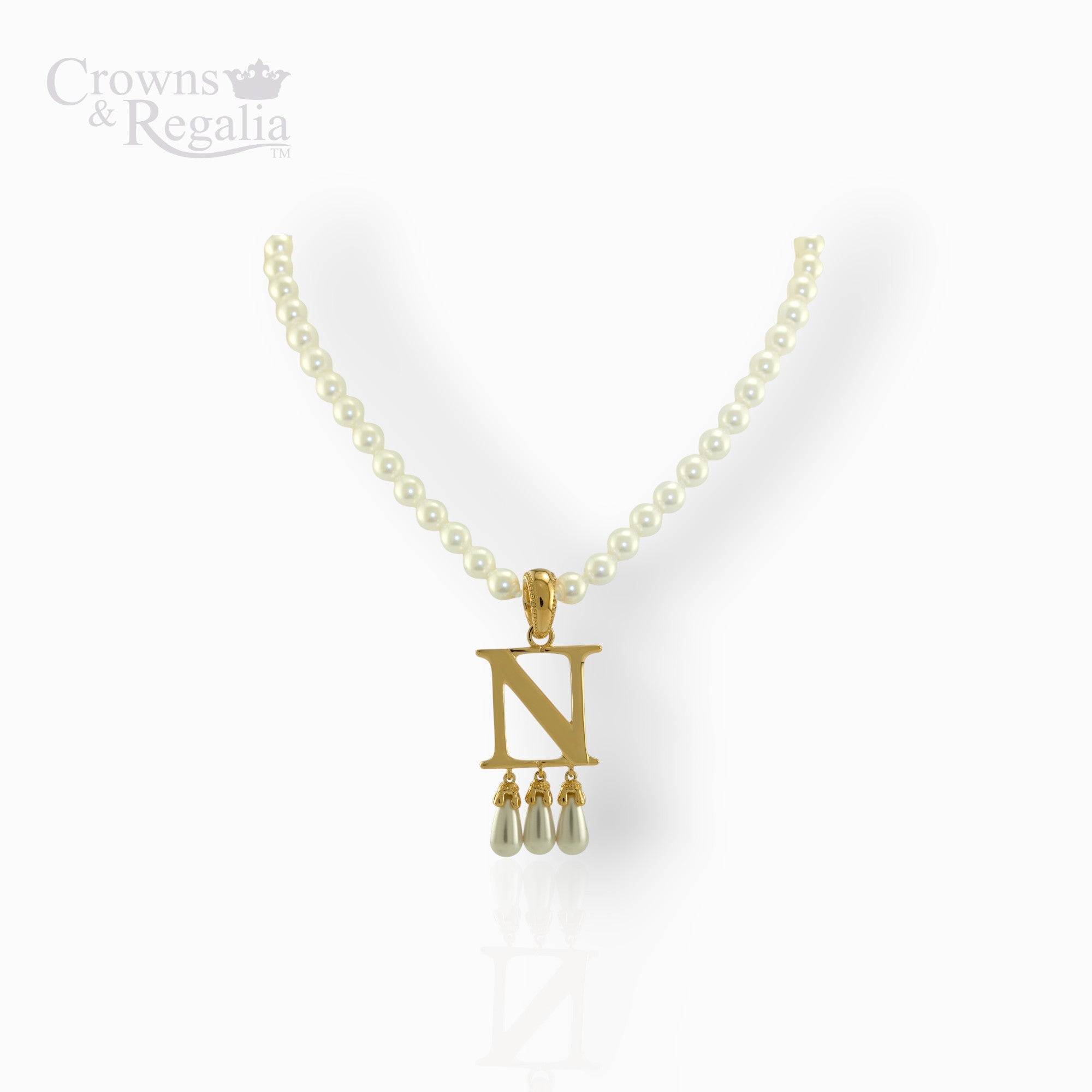 Pearl necklace with a gold pendant labeled 'N' on a white background, featuring the brand 'Crowns & Regalia'.