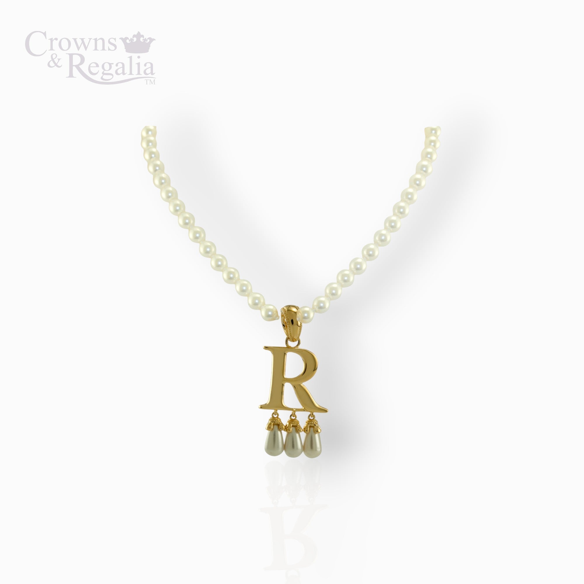 Gold necklace with 'R' pendant and pearl drops on a white background, branded 'Crowns & Regalia'.